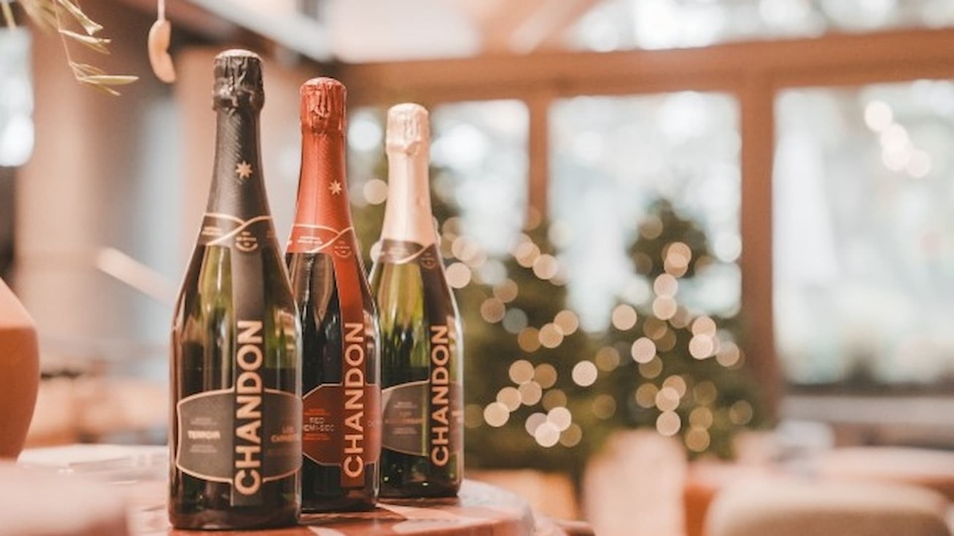 Three Chandon bottles on a table, festive background.