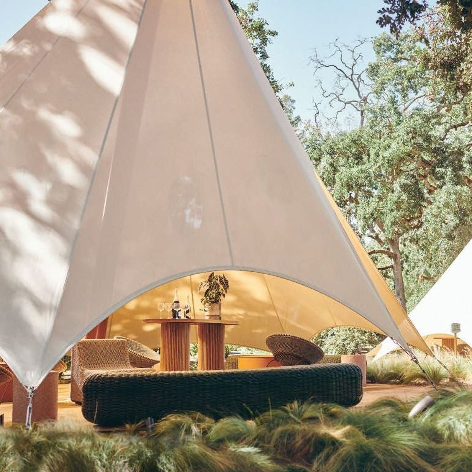 Outdoor glamping tent with seating and table.