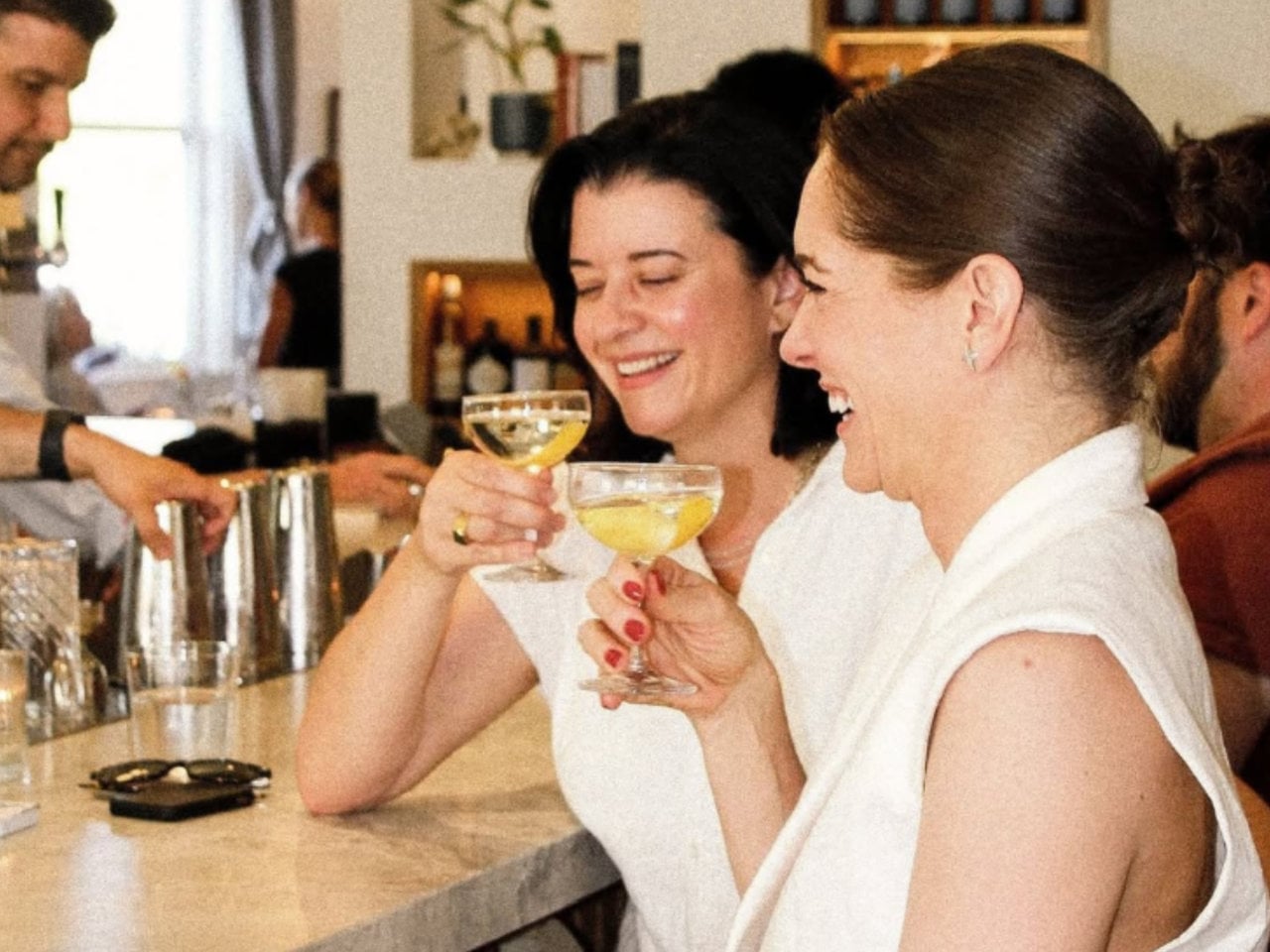 Two women toasting cocktails at a bar