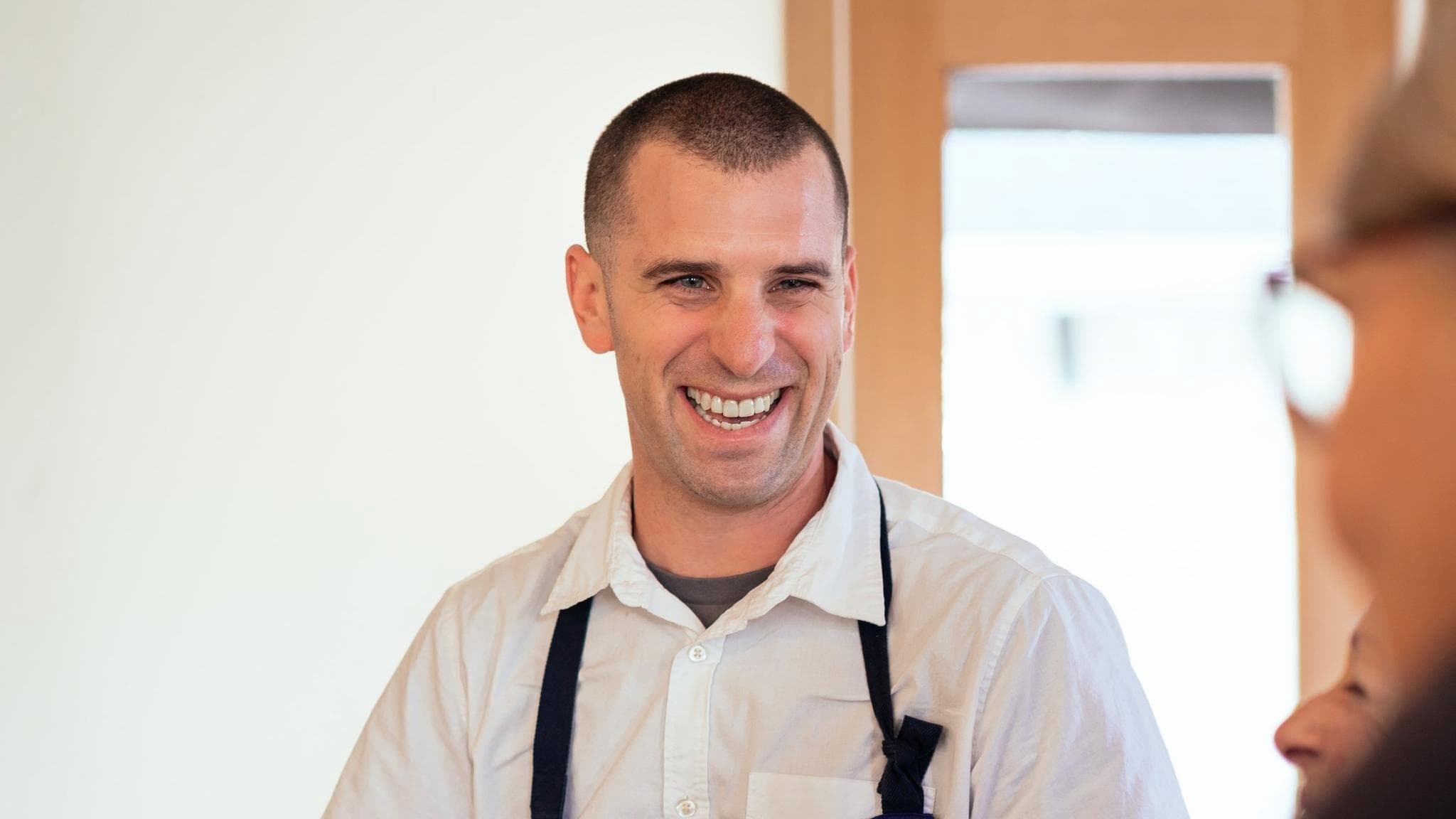 Smiling person wearing a white shirt and apron.