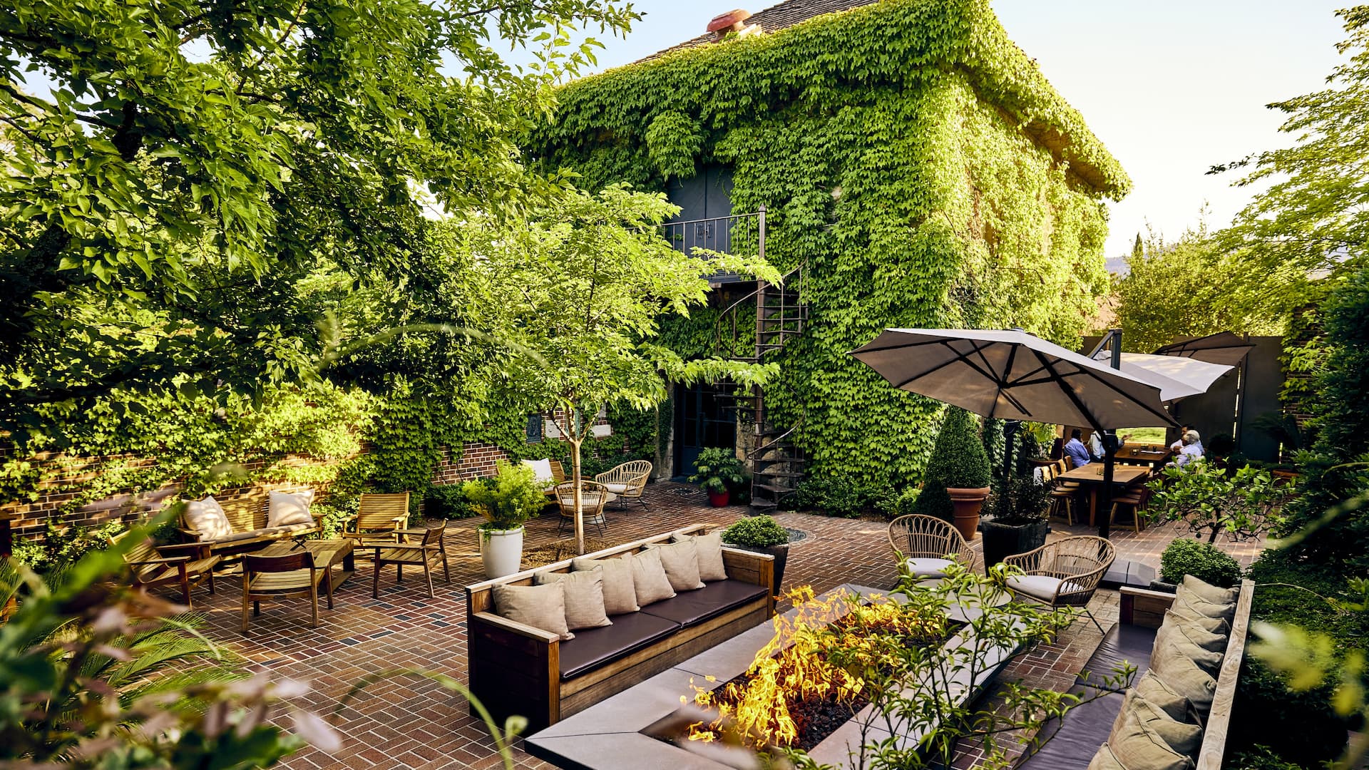 Lush garden patio with seating and umbrellas.