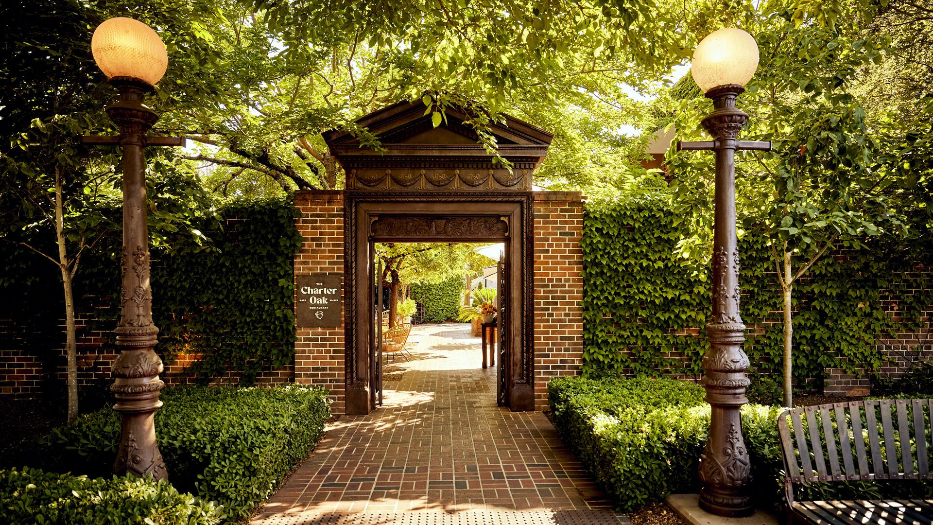 Brick entrance to garden patio with lampposts.