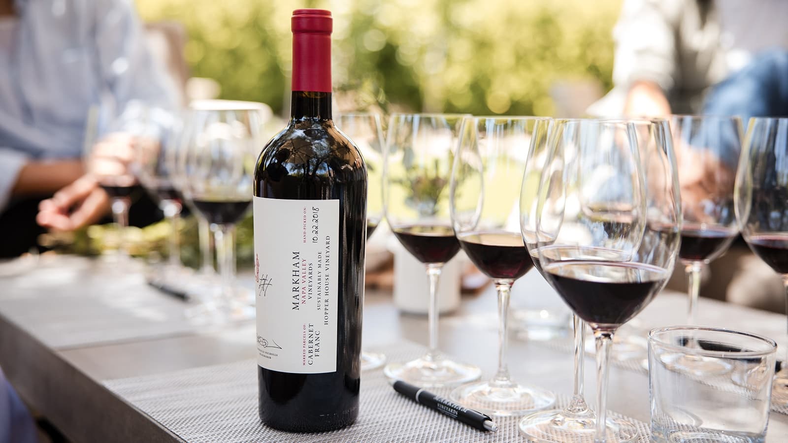 Wine bottle and glasses on table outdoors.