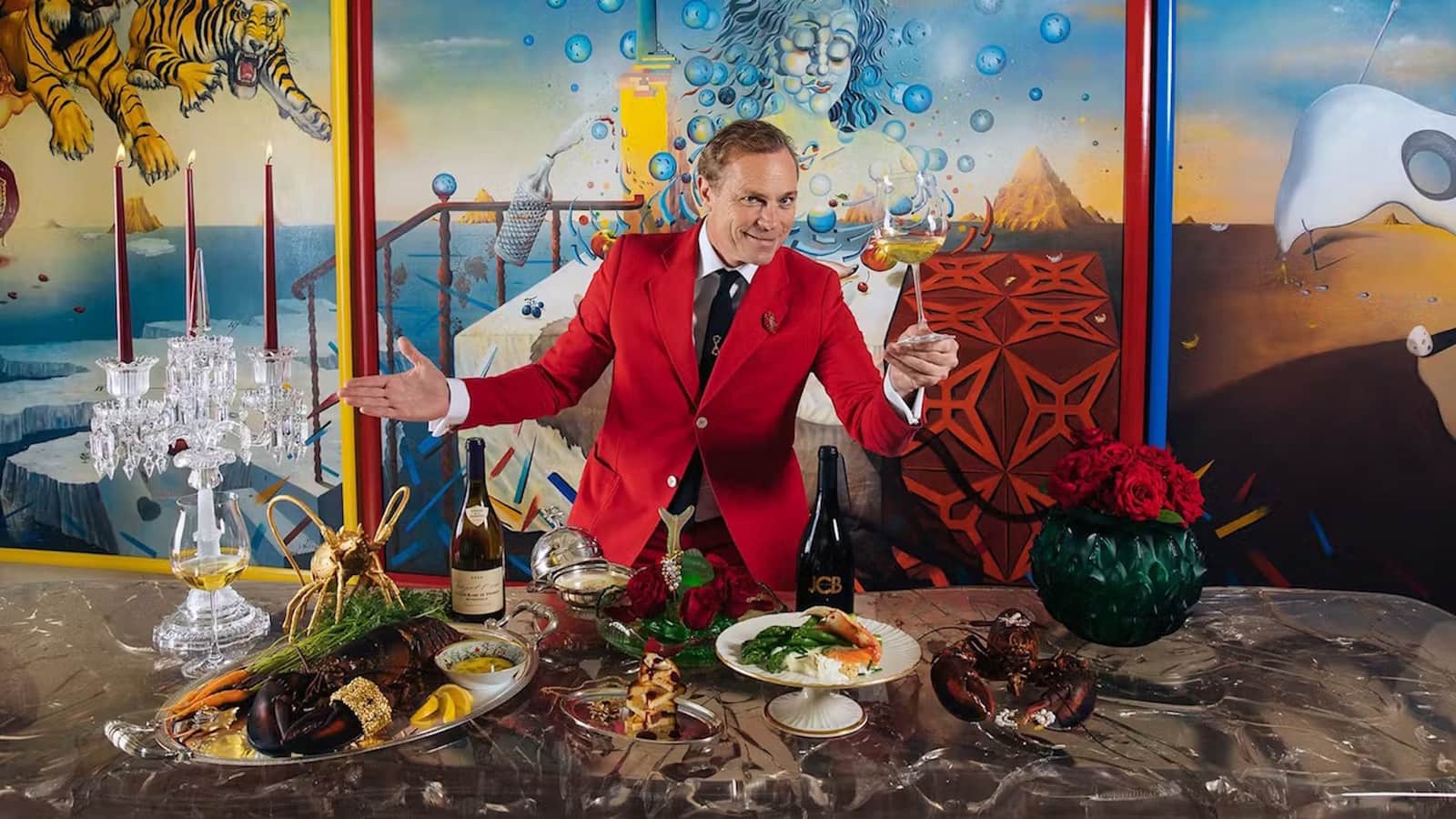 Man in red jacket with gourmet dinner table.