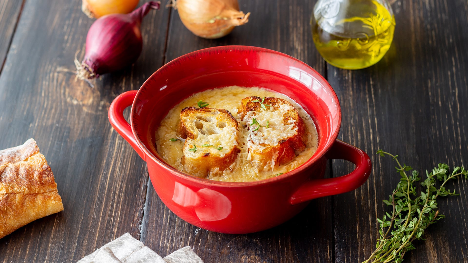 French onion soup with cheesy toast in red bowl