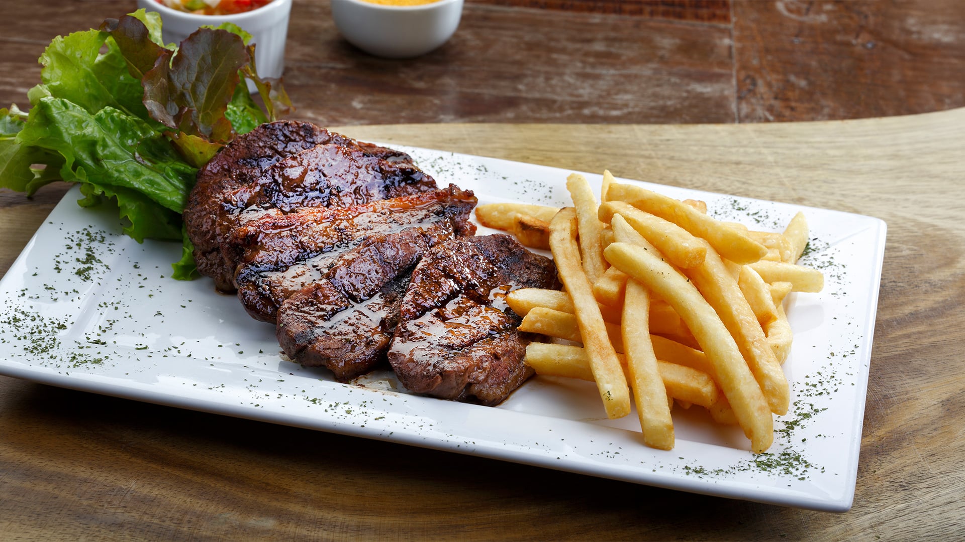 Sliced steak with French fries on white plate