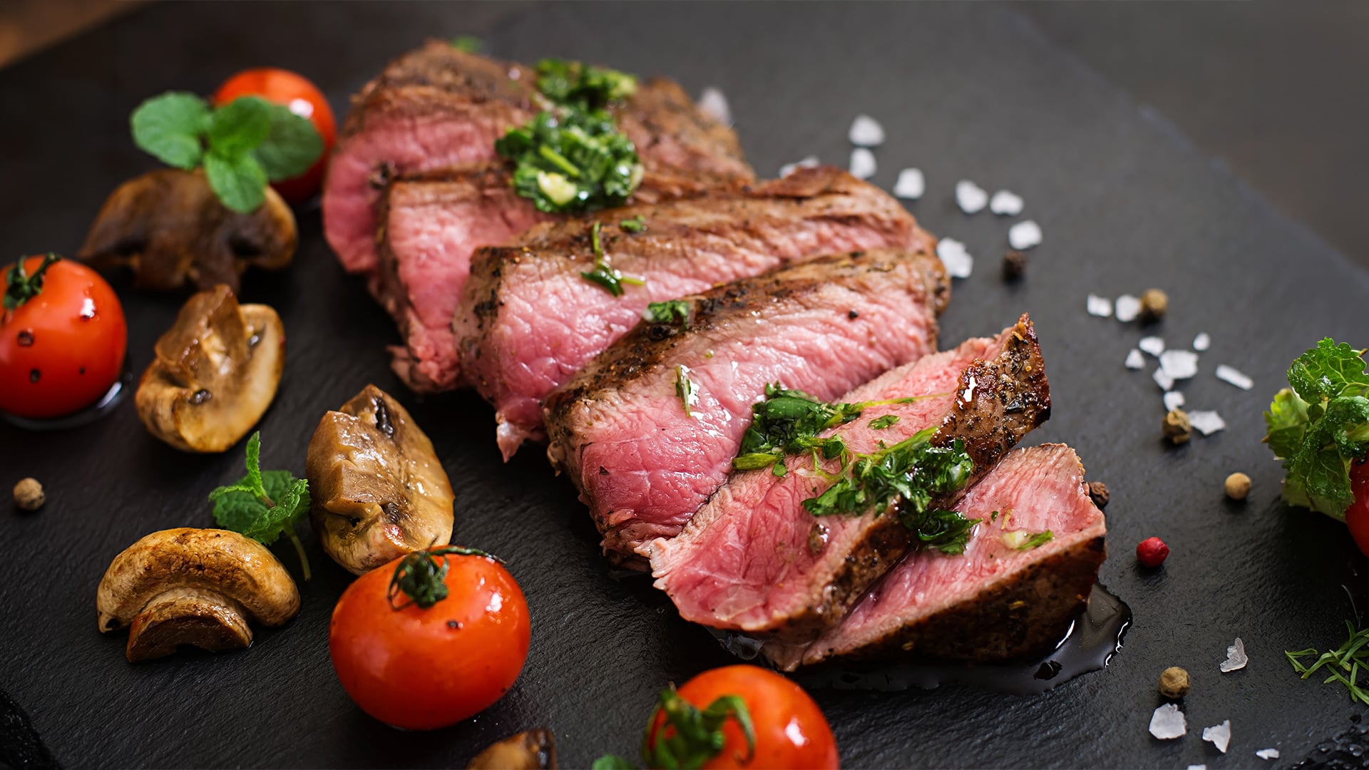 Sliced medium-rare steak with herbs and vegetables