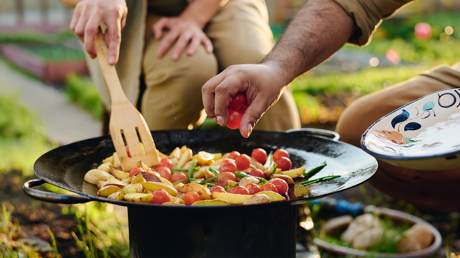 Adding cherry tomatoes to skillet in garden