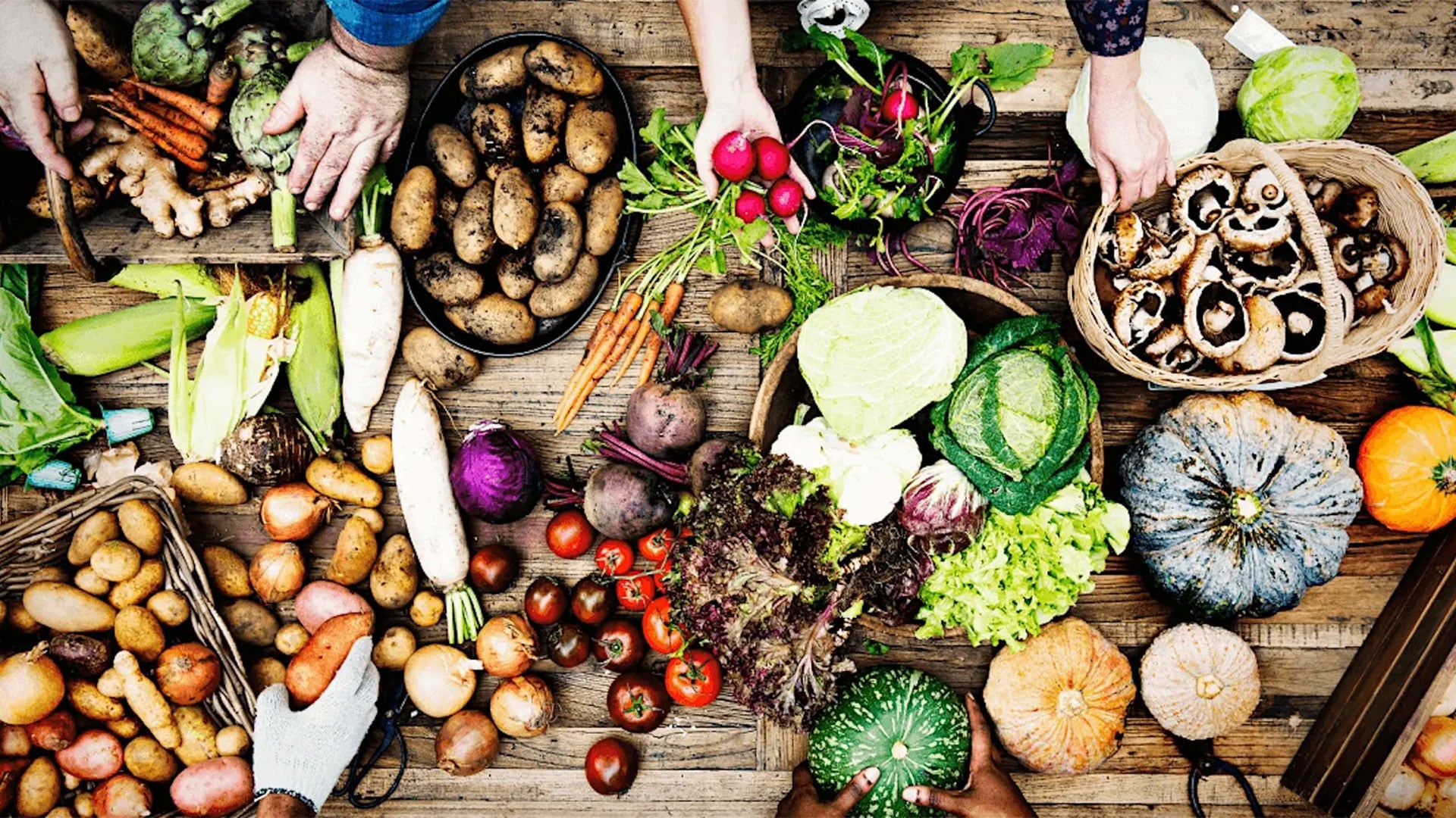 Overhead view of assorted fresh vegetables on wooden table