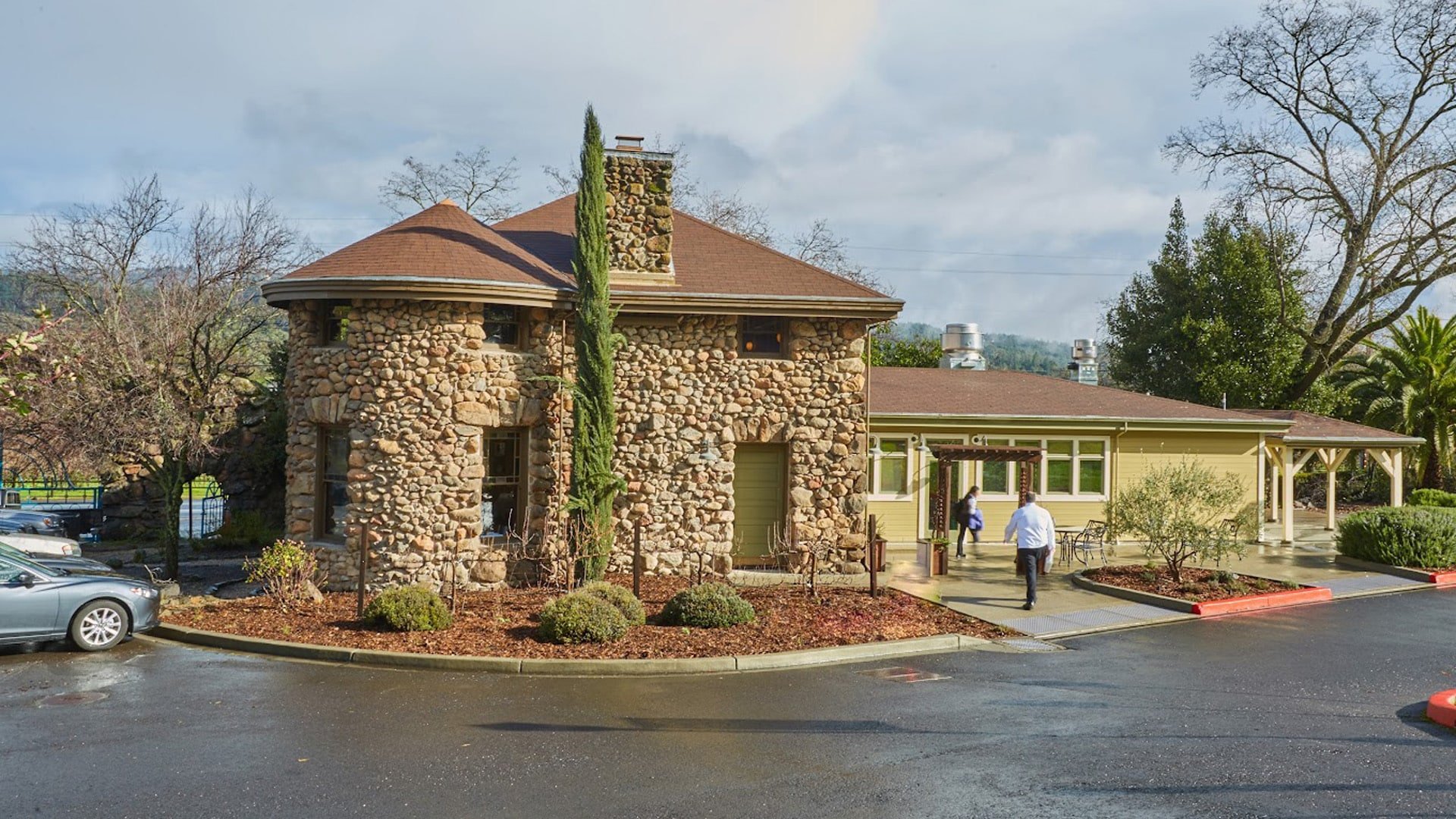 Stone building with circular tower and parking area.