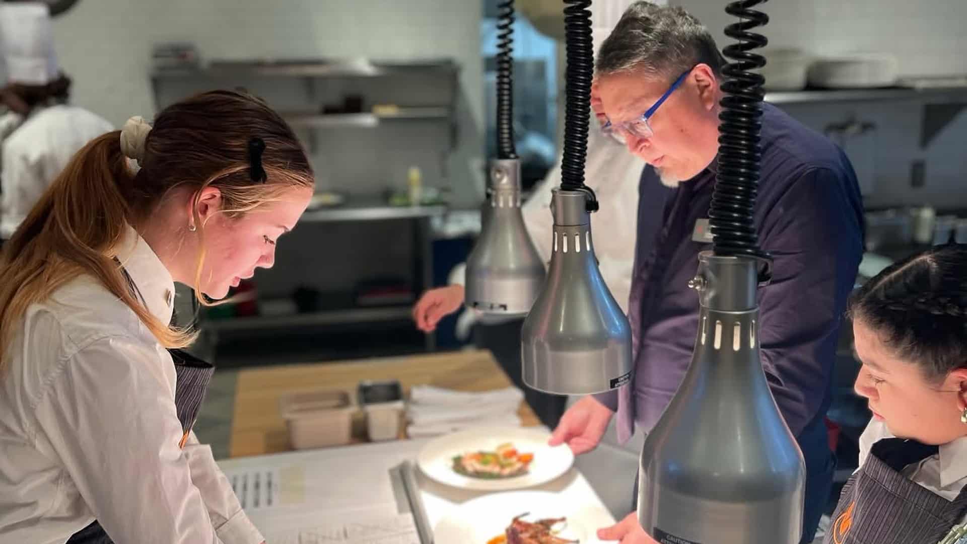 Chefs preparing dishes in restaurant kitchen.