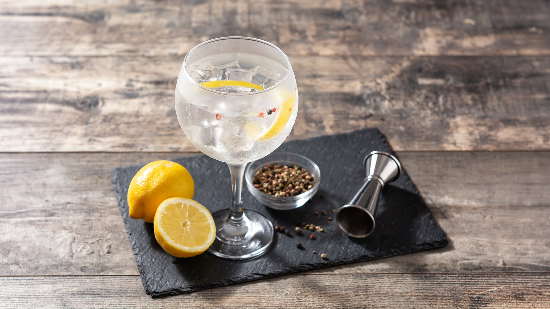 Iced lemon cocktail with peppercorns on slate board