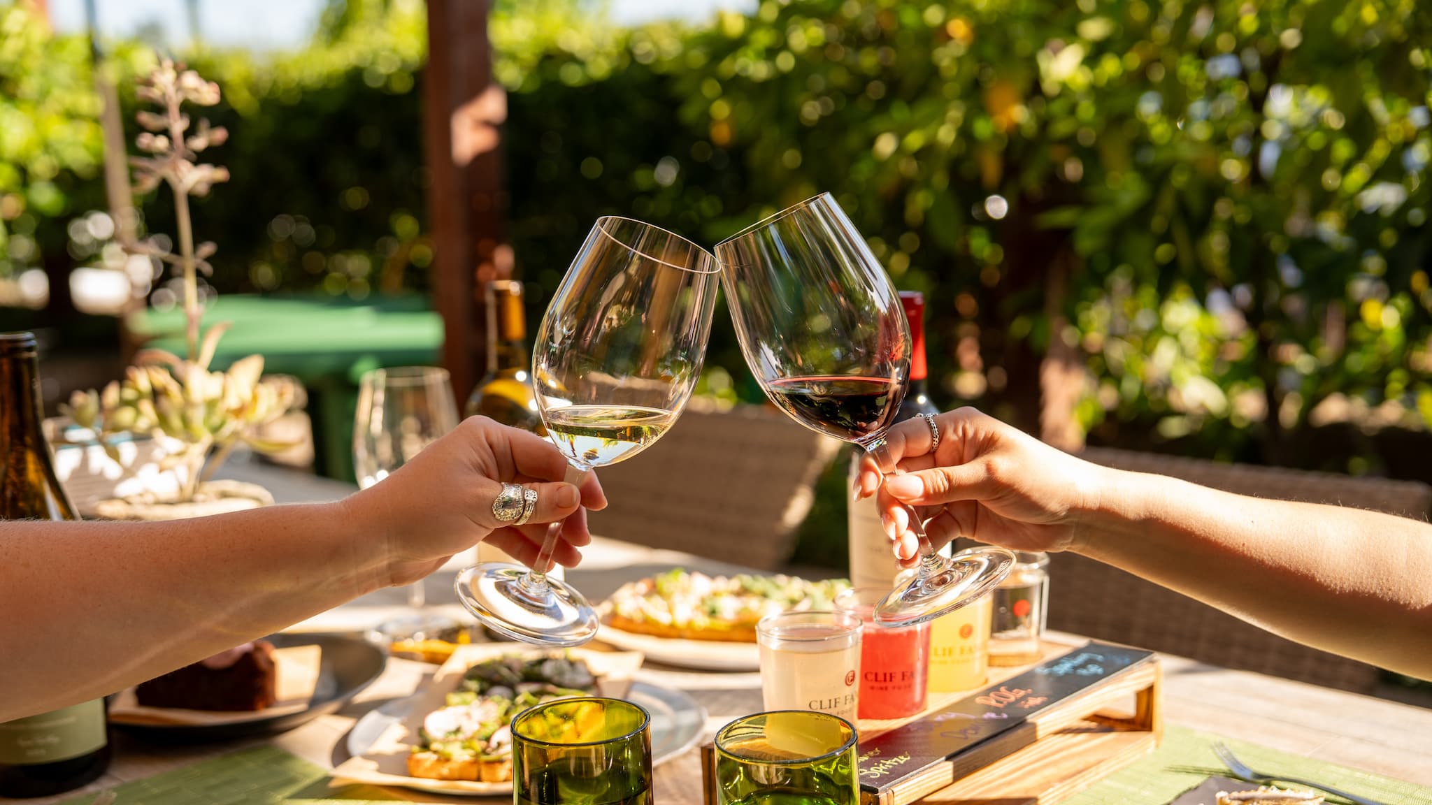 Two people clinking wine glasses at outdoor table