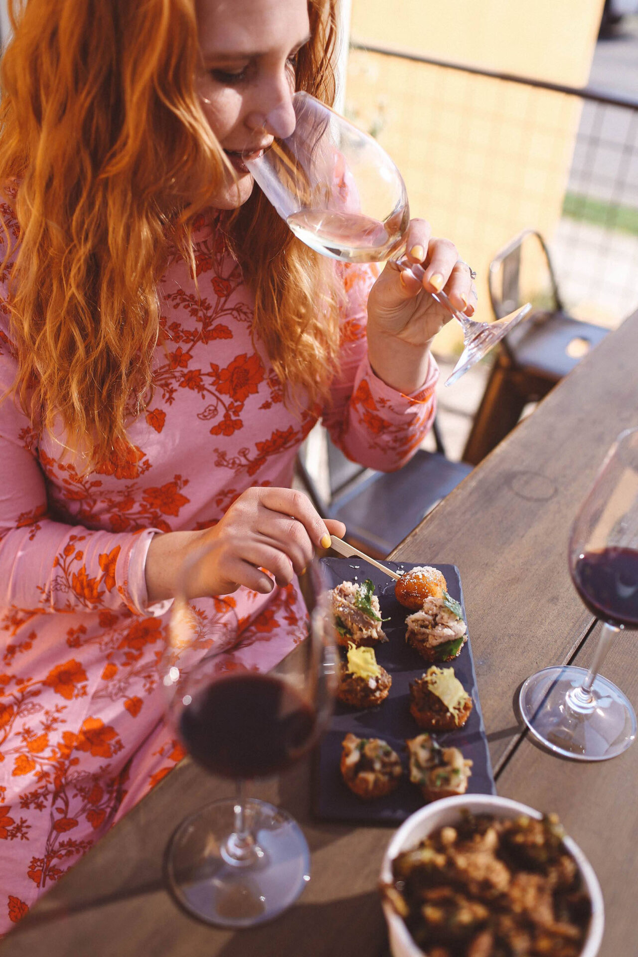 Woman enjoying wine and appetizers at a table.