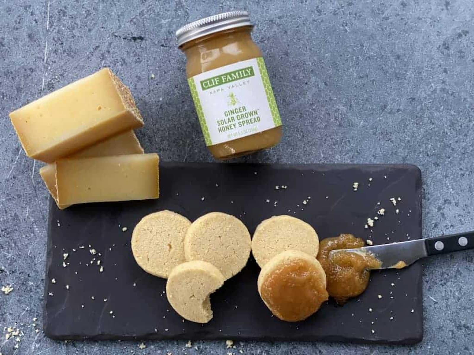 Cheese, cookies and honey spread on slate board.