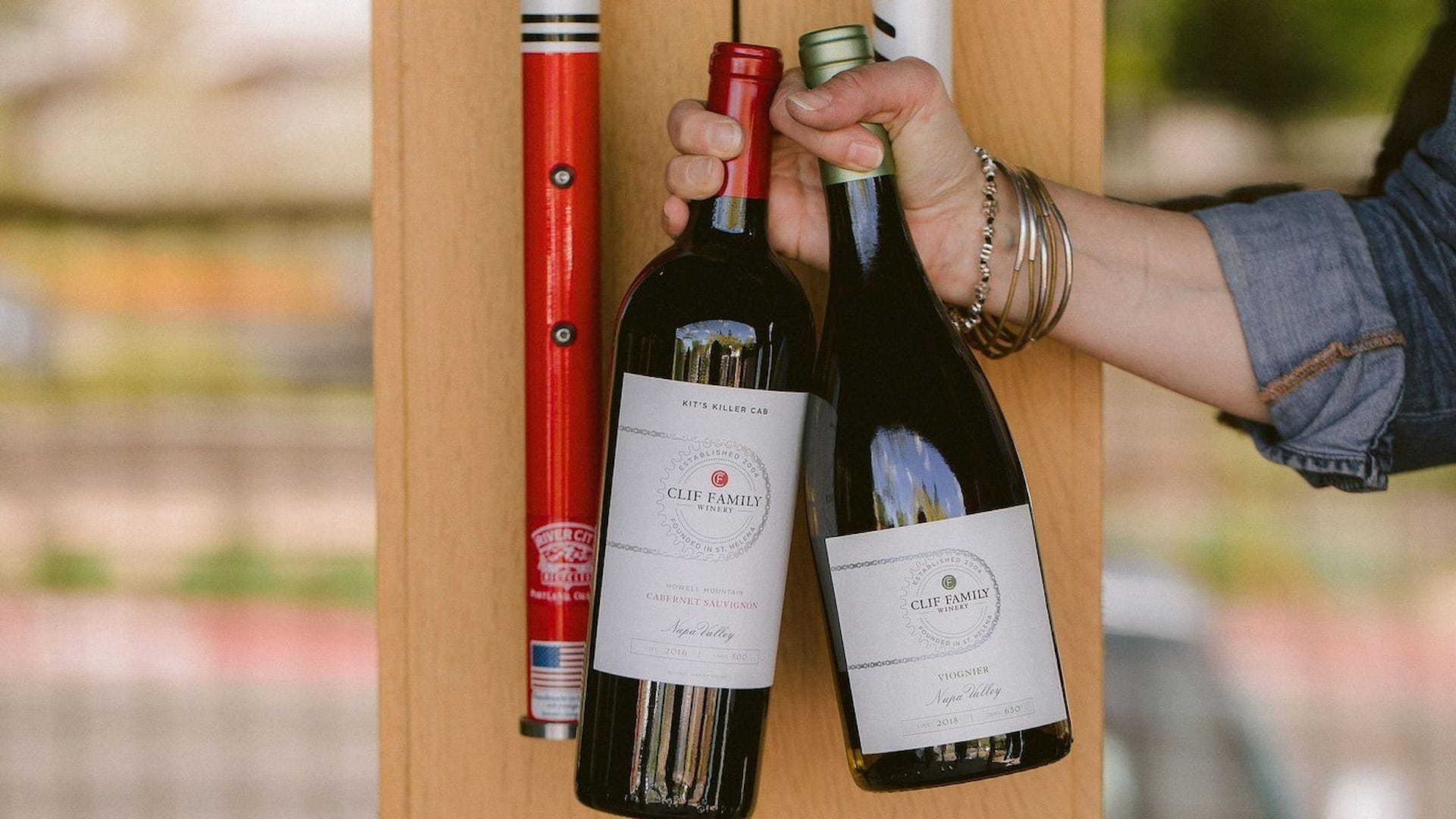 Hand holding two Clif Family wine bottles.