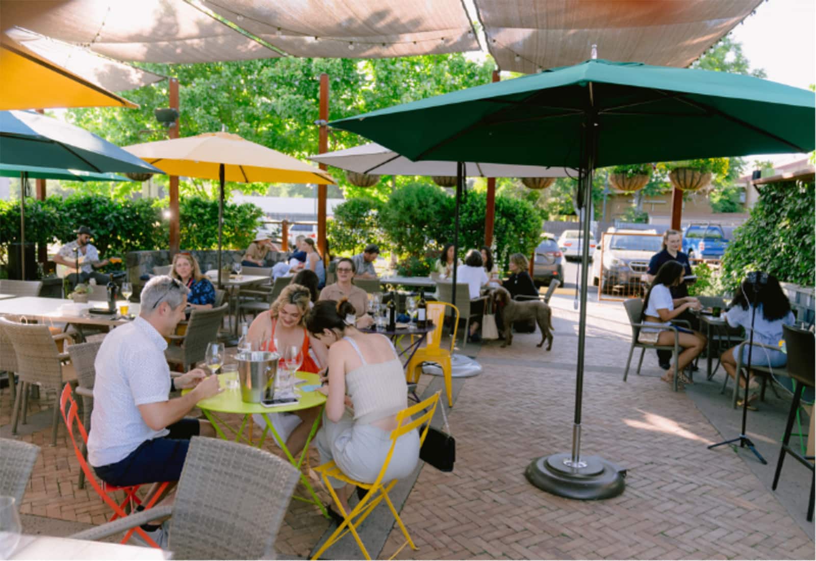 Outdoor café with people dining and umbrellas.