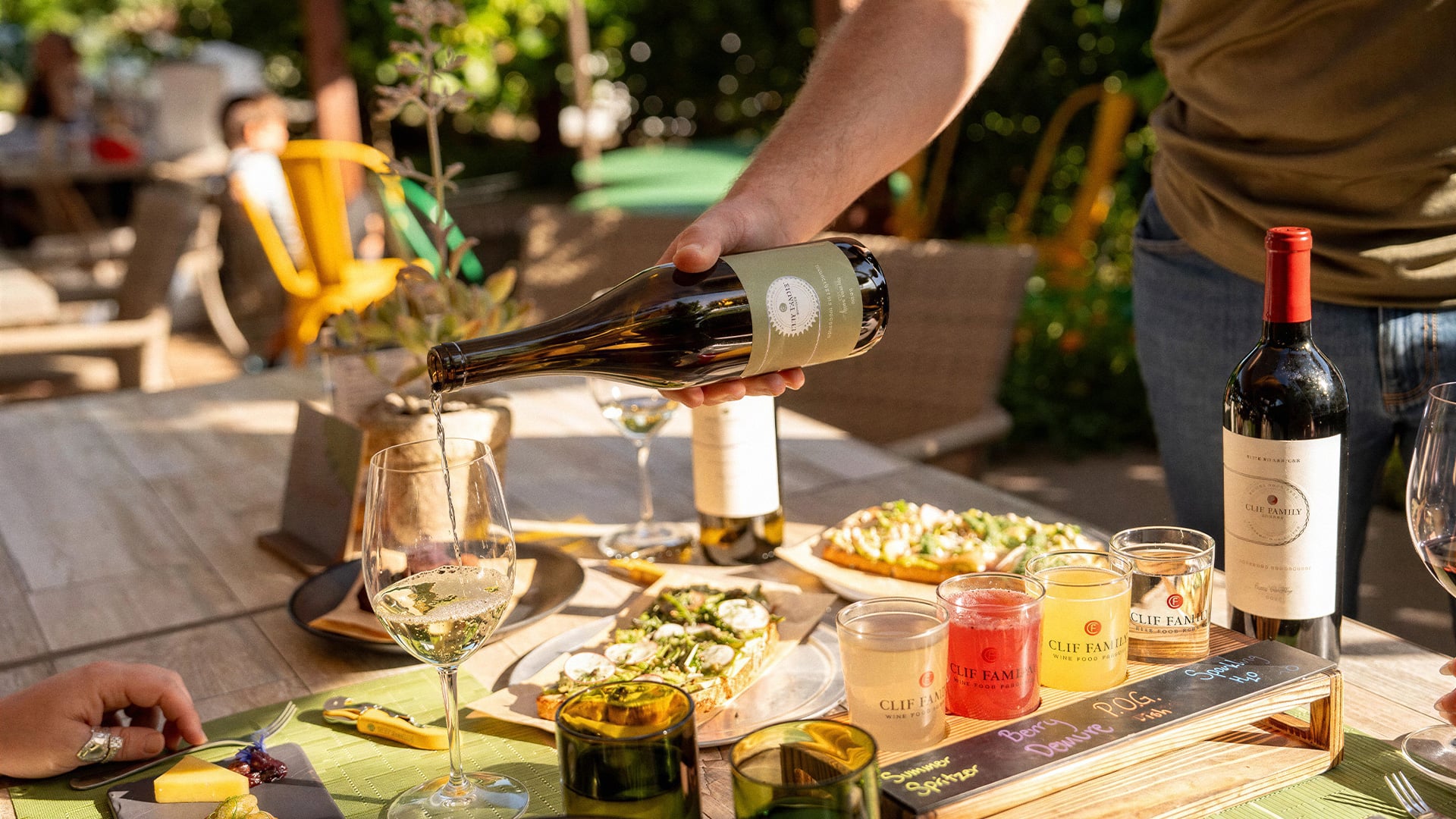 Person pours white wine at an outdoor meal