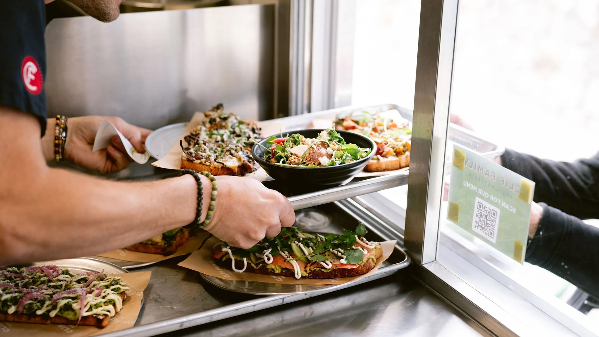 Server passes salads and open-faced sandwiches through window.