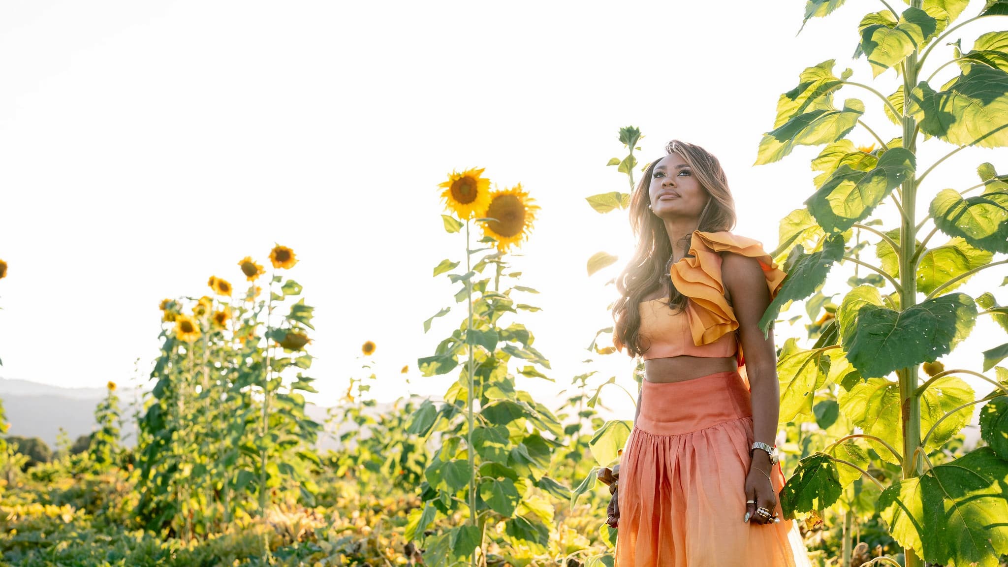 Woman in orange dress standing in sunflower field