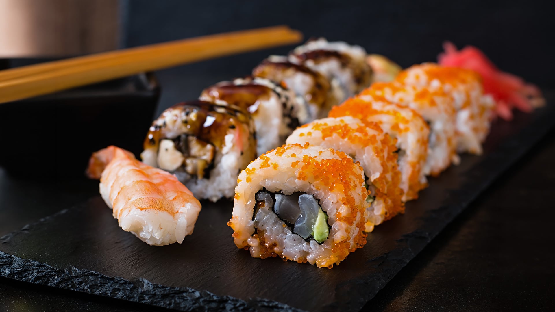 Assorted sushi rolls and shrimp nigiri on slate platter