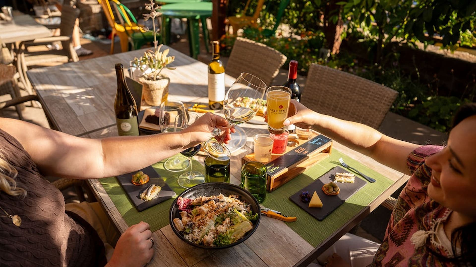 Friends toasting drinks at sunny outdoor restaurant table