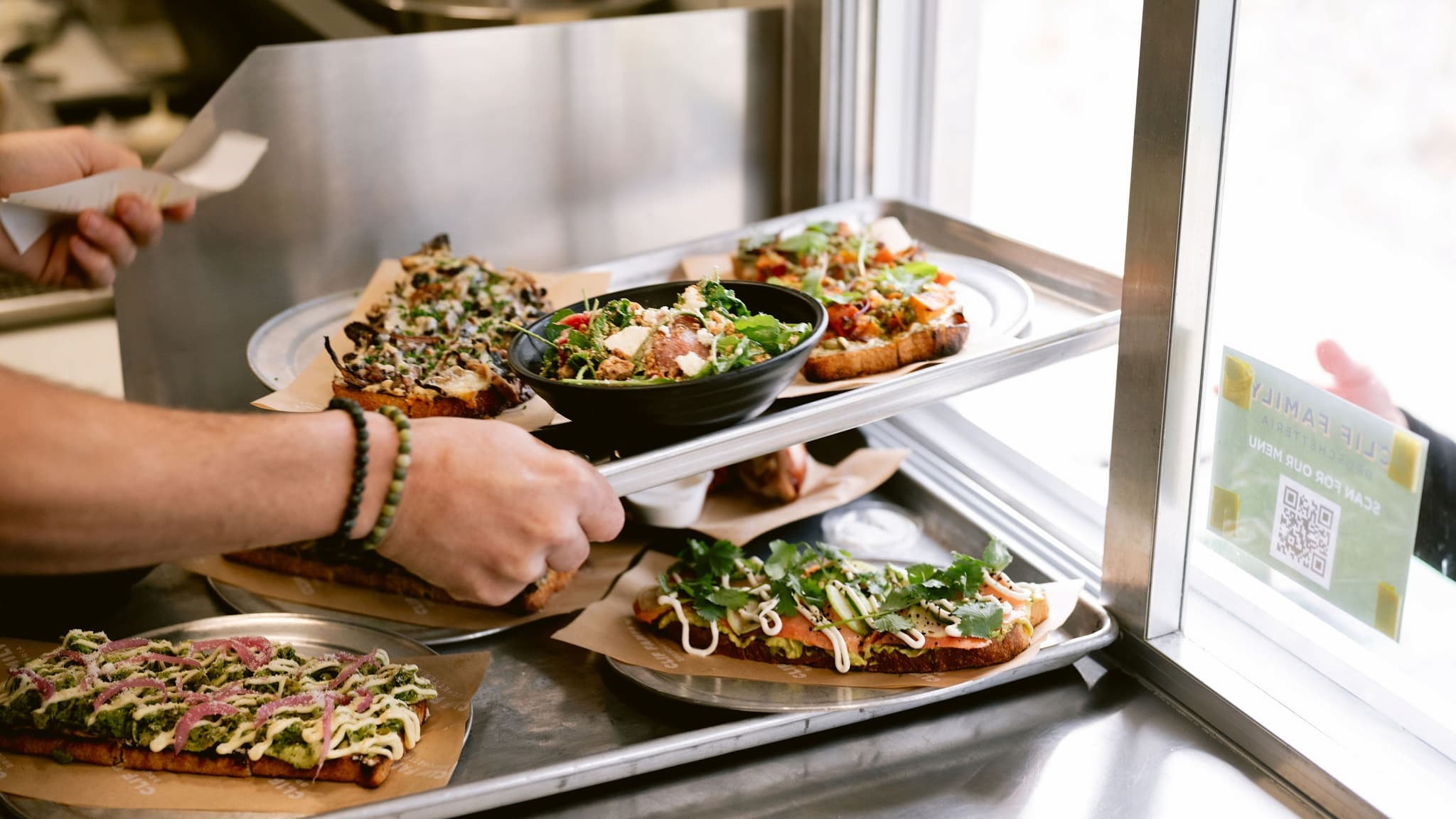 Person serving salads and gourmet toasts at counter