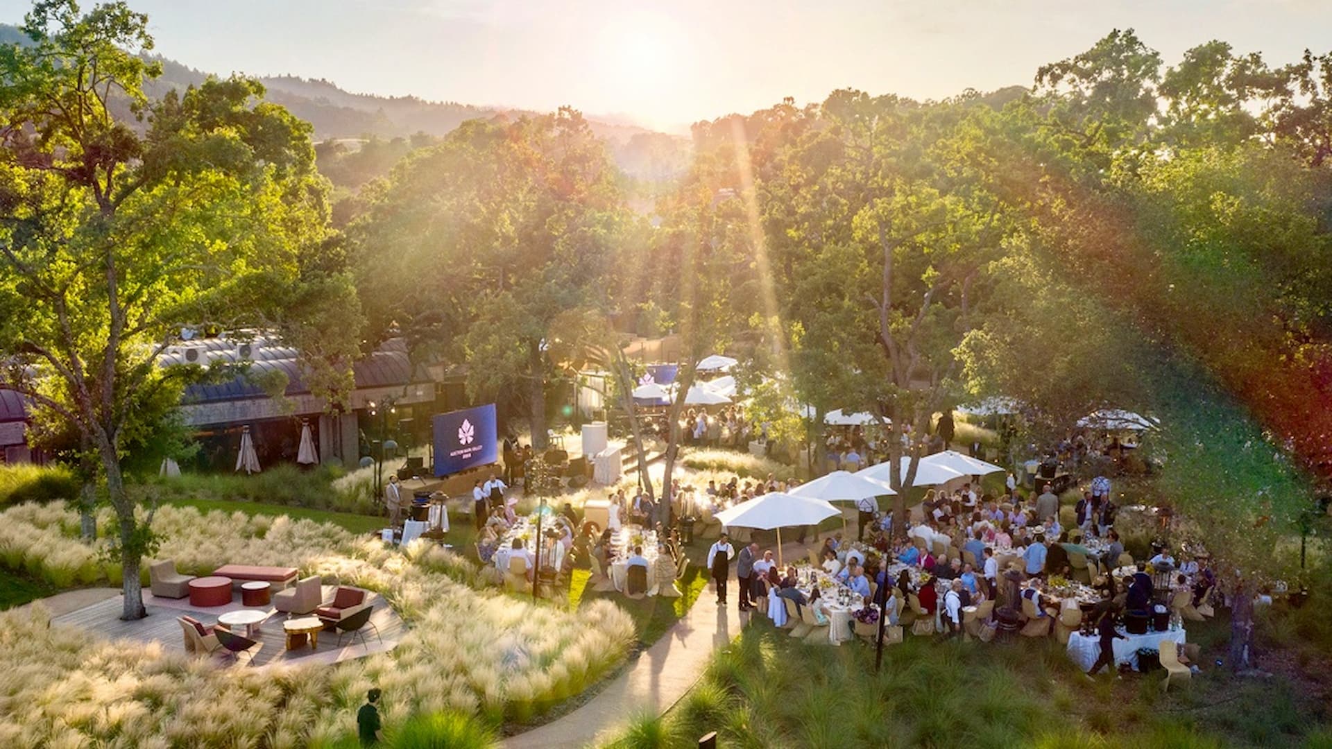 Outdoor garden event with tables and people.