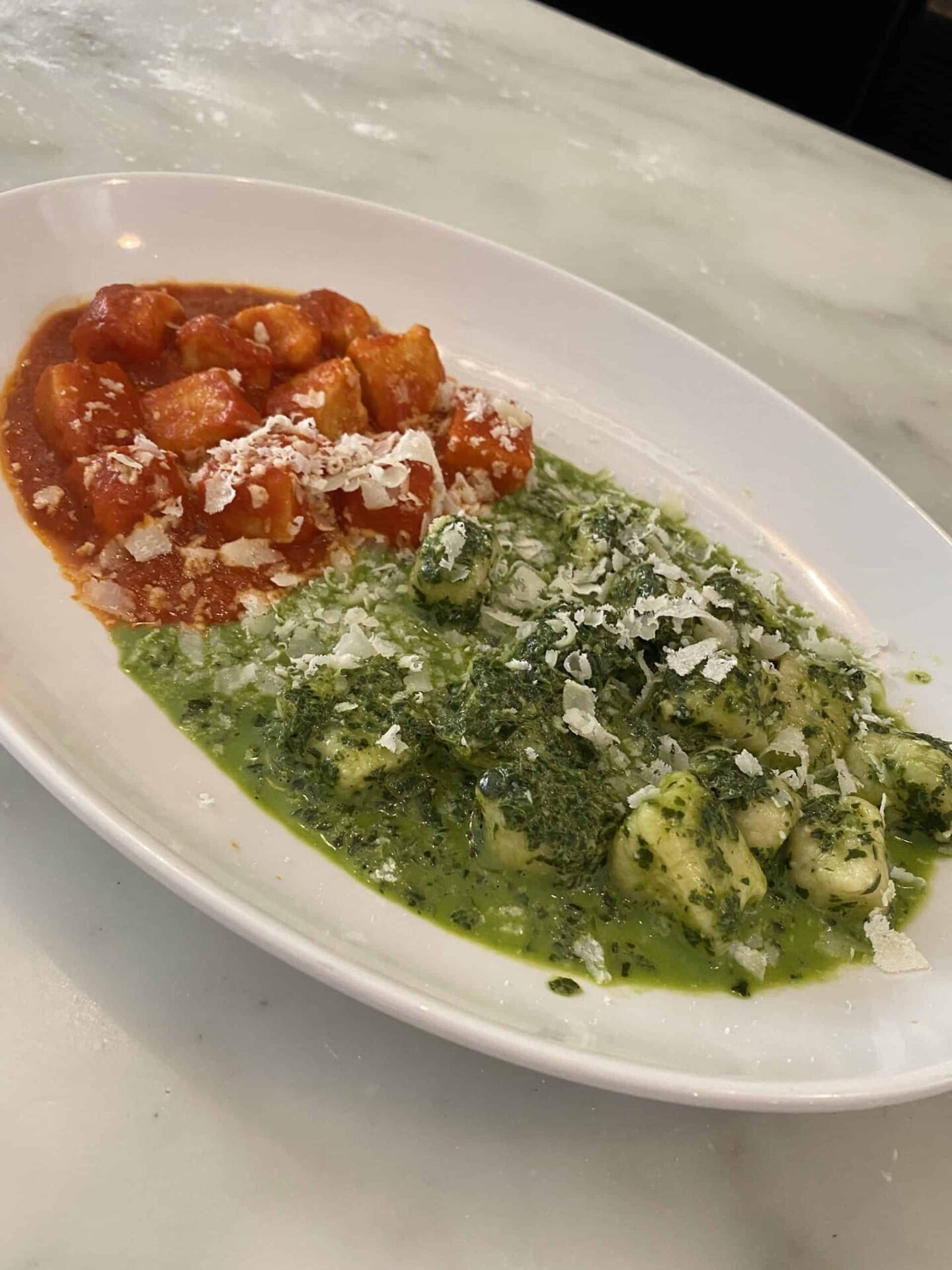 Gnocchi with red sauce and pesto on a plate.