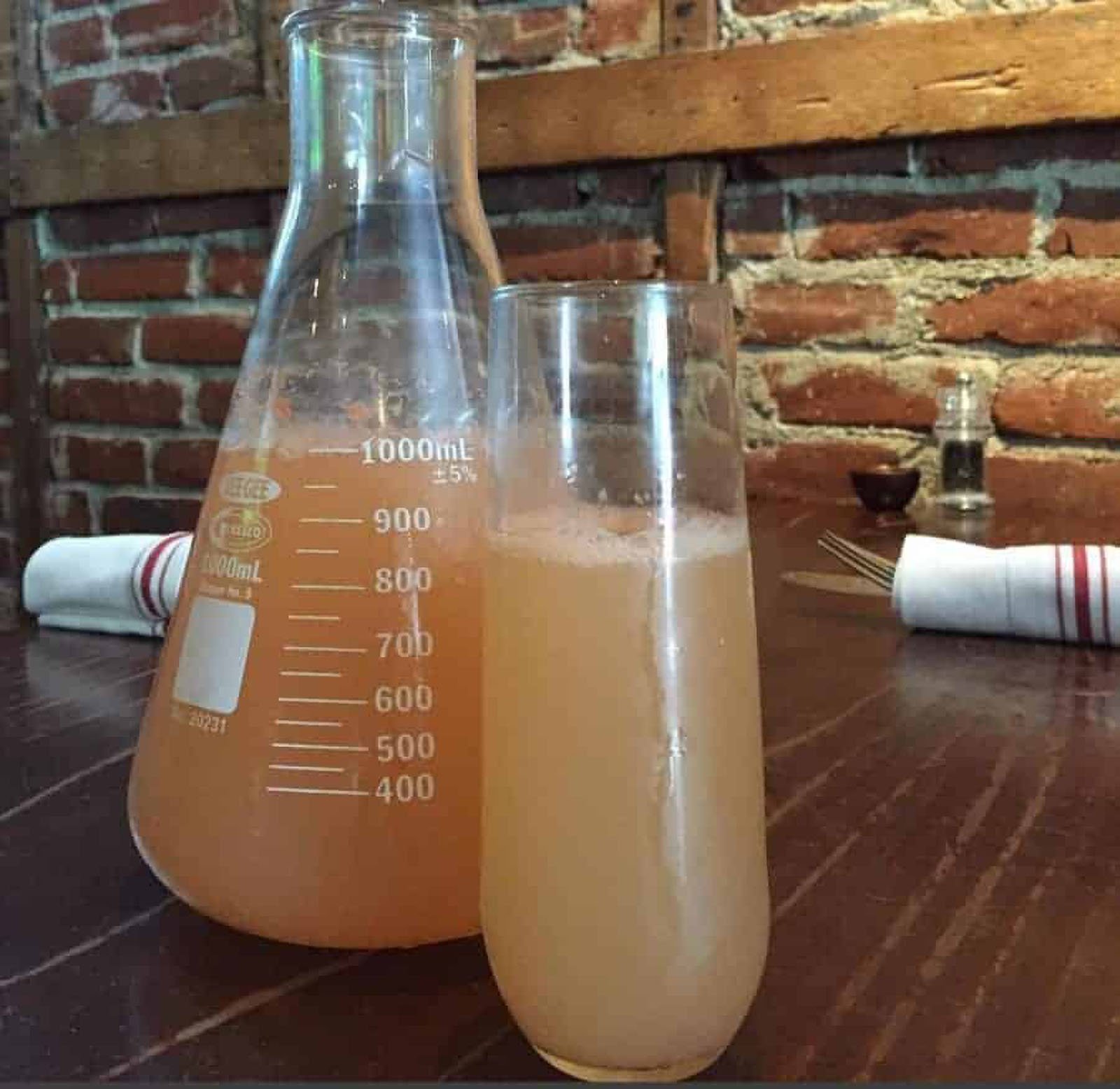 Orange drink in flask and glass on table.