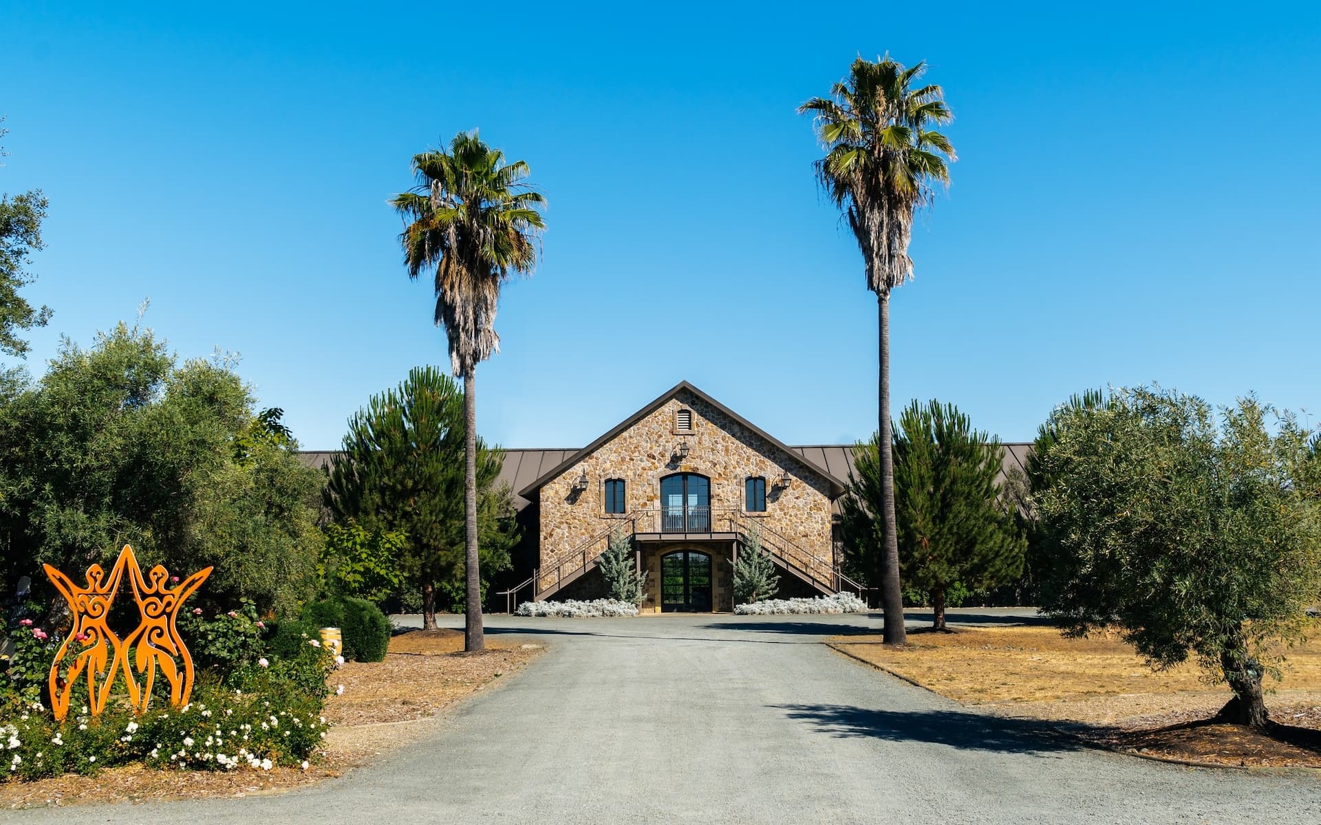Stone building with palm trees and sculpture