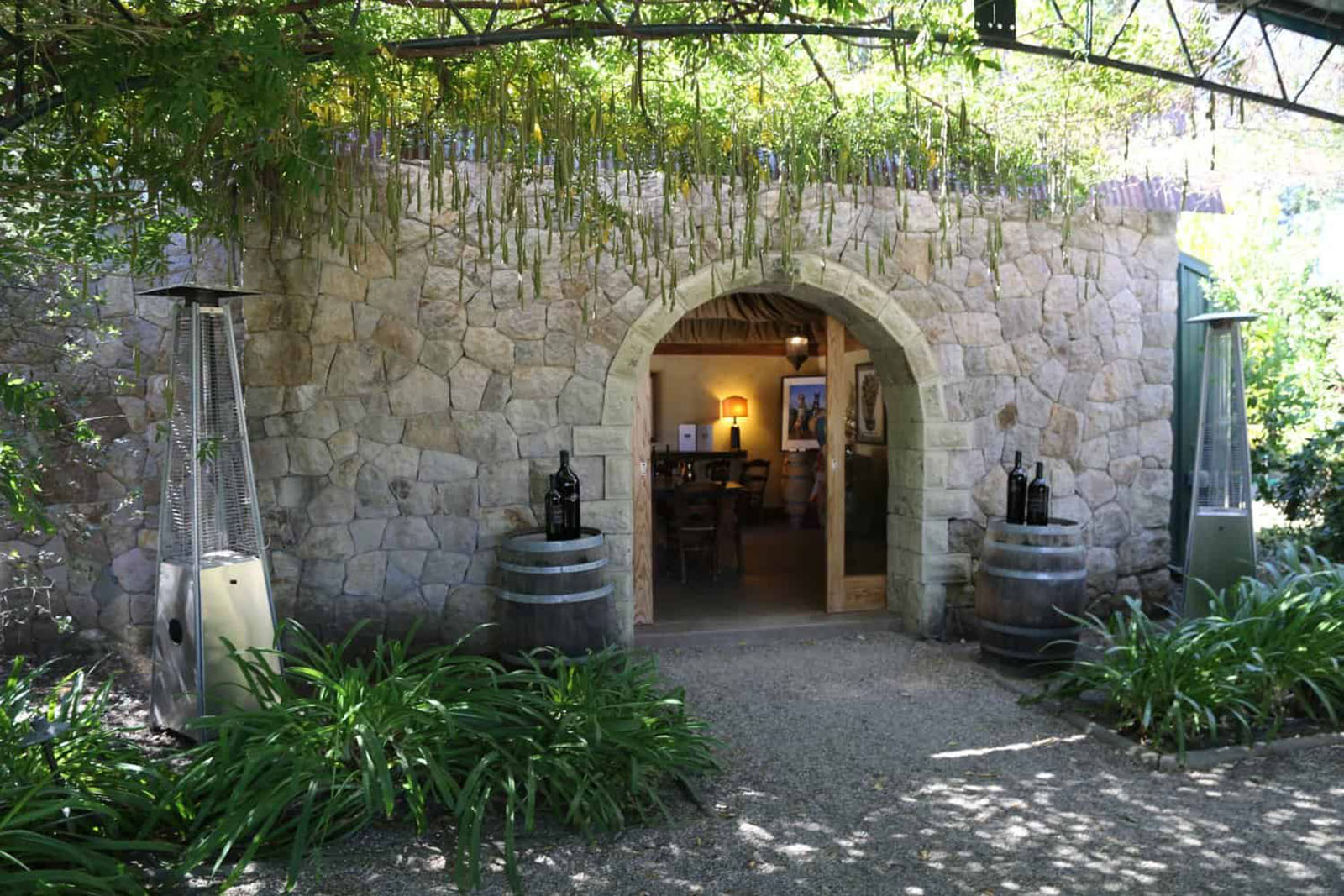 Stone building entrance with wine barrels and heaters.