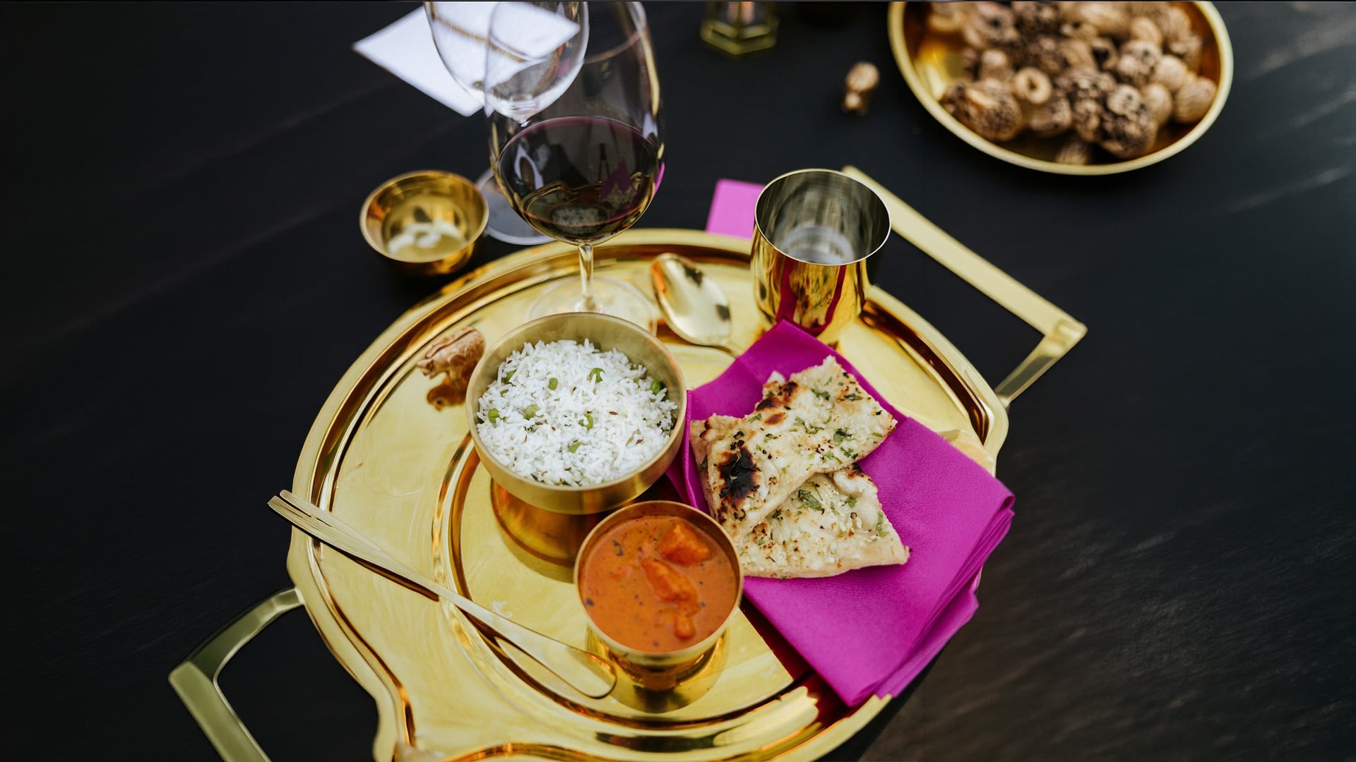 Indian meal on gold tray with red wine