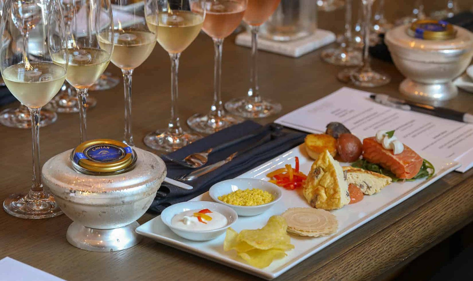 Gourmet platter with caviar, appetizers, and wine glasses.