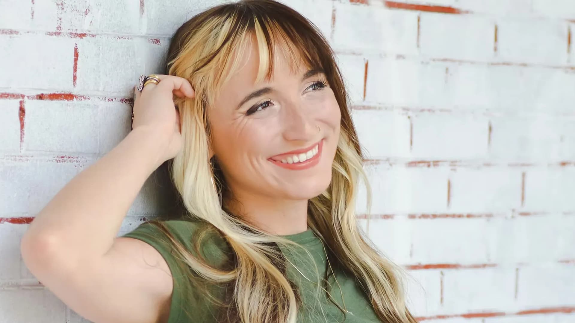 Smiling woman leaning against brick wall