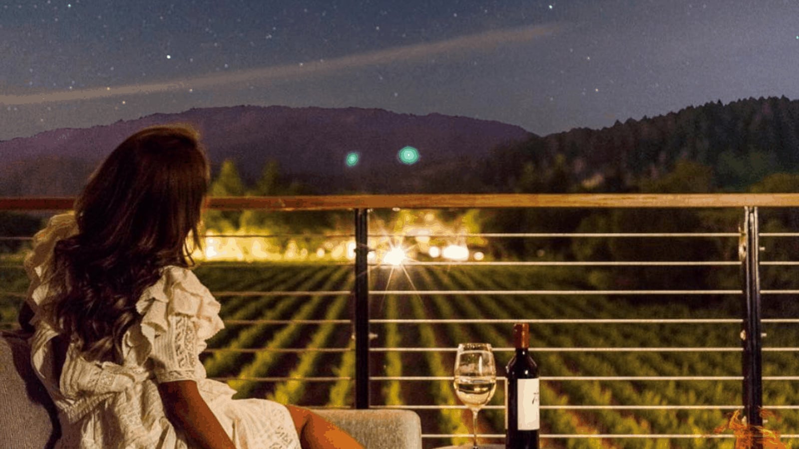 Woman enjoying vineyard view under starry night sky.