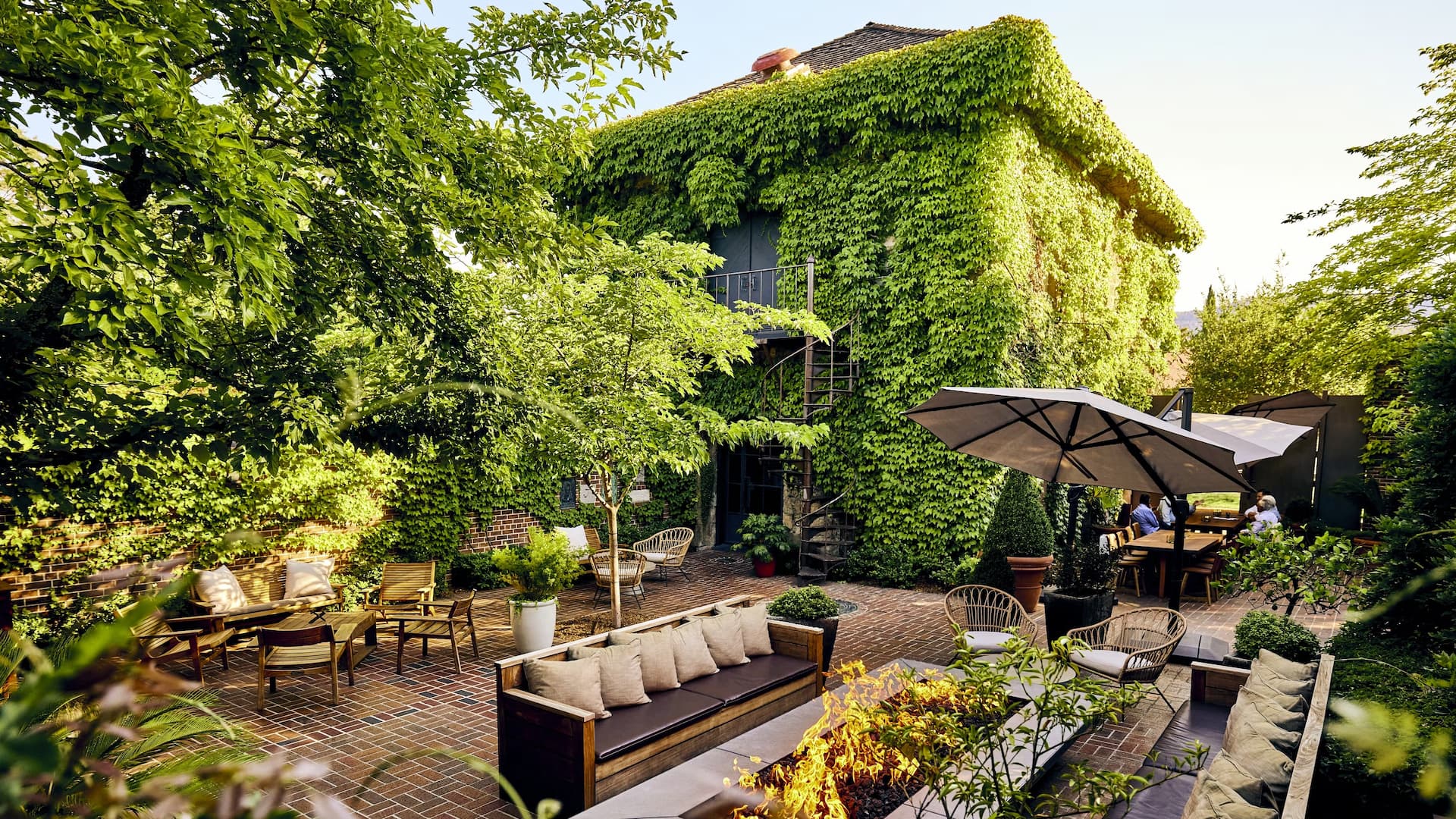 Lush garden patio with ivy-covered building and seating.
