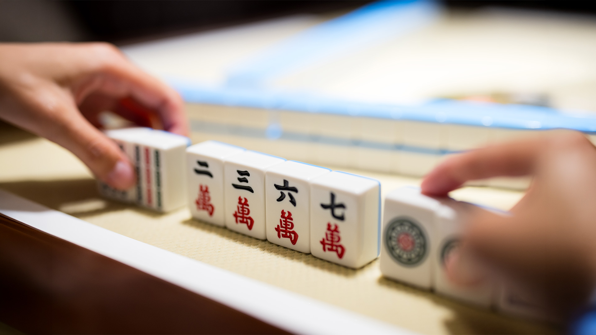 Hands arranging mahjong tiles on table