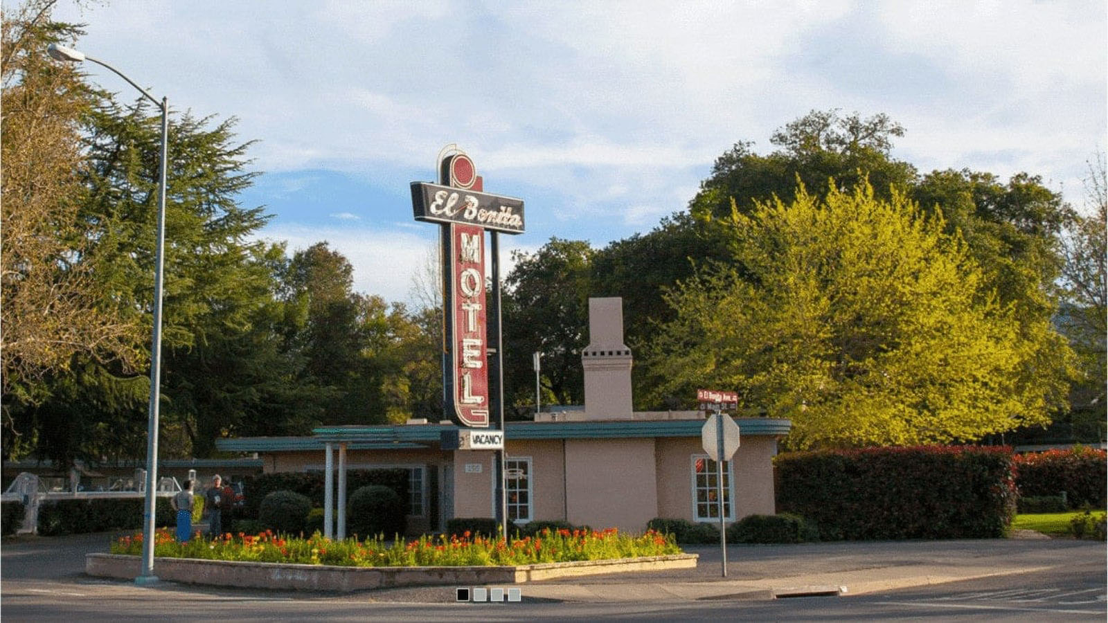 Vintage motel with neon sign in lush surroundings.