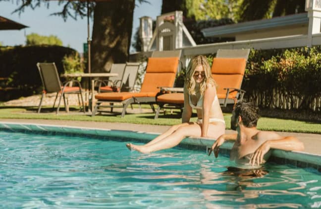 Couple relaxing by a sunny backyard swimming pool