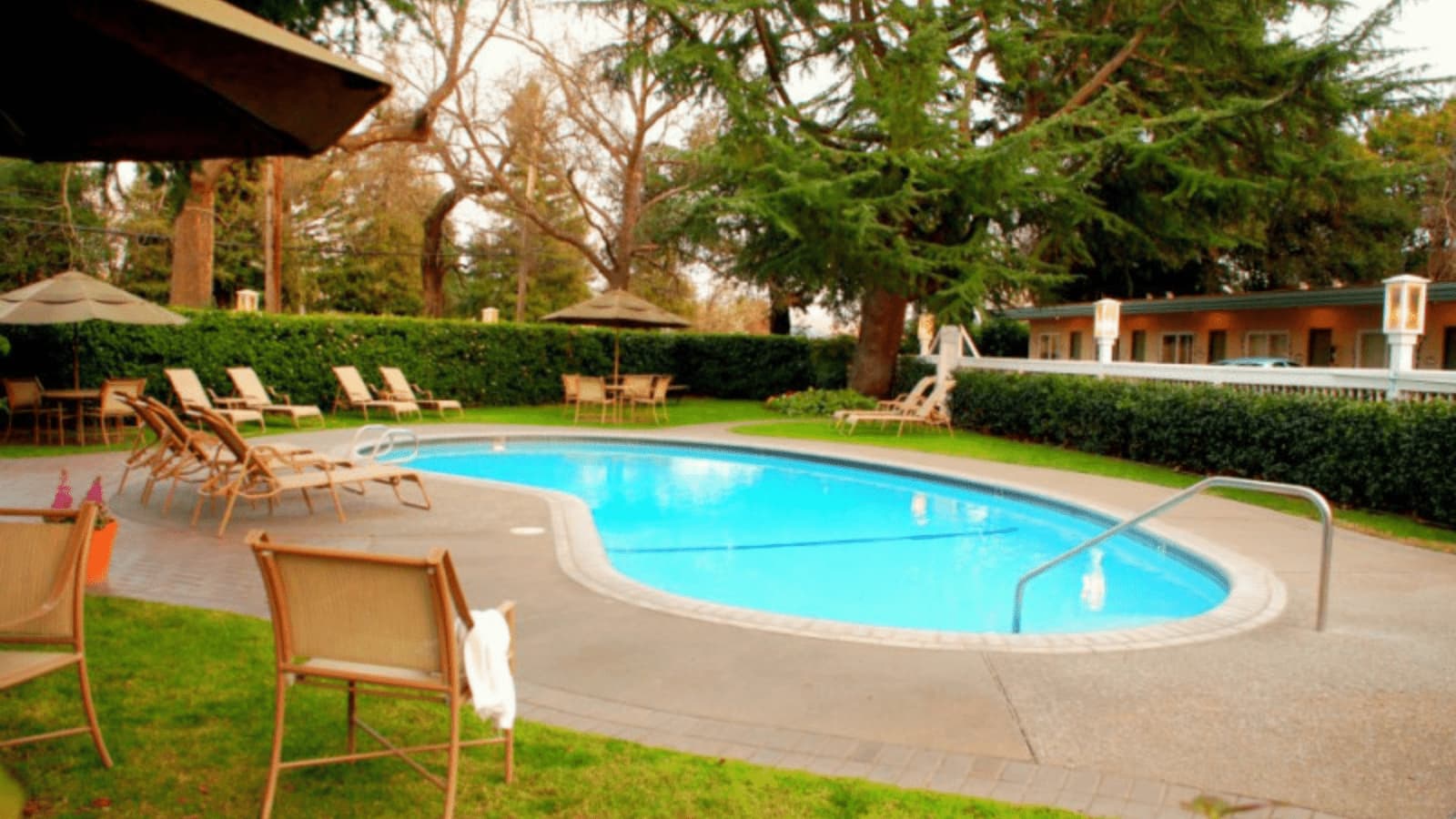Outdoor swimming pool with lounge chairs and umbrellas.