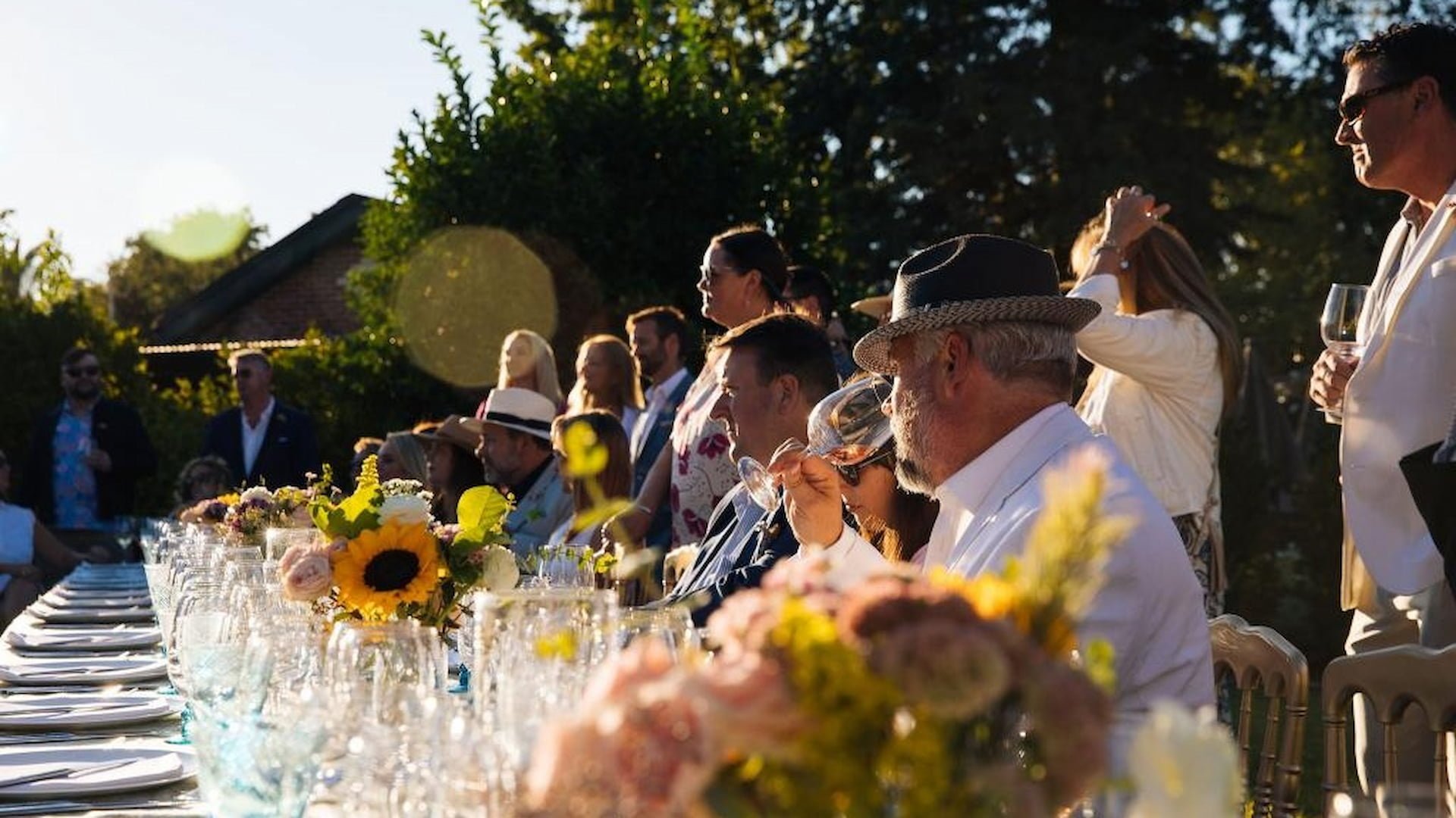Outdoor dinner event with guests and floral table decorations.