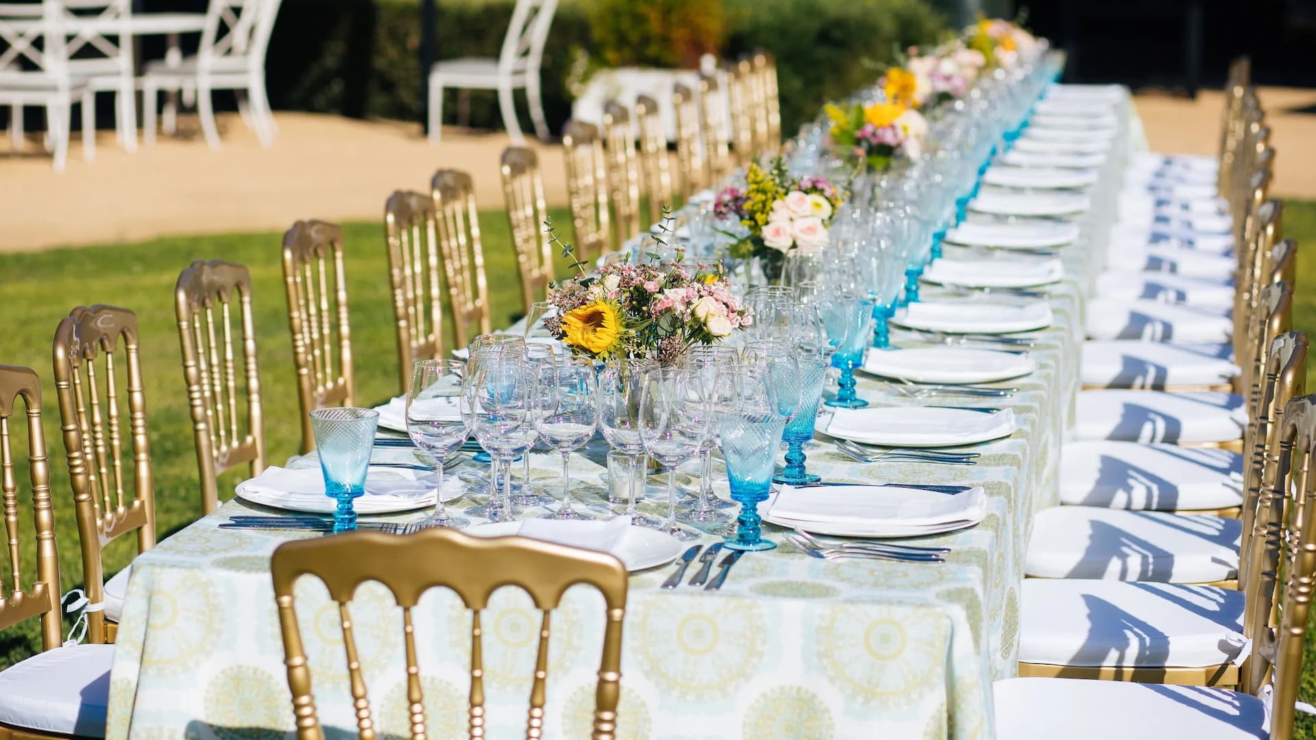 Outdoor table setup with flowers and glassware.