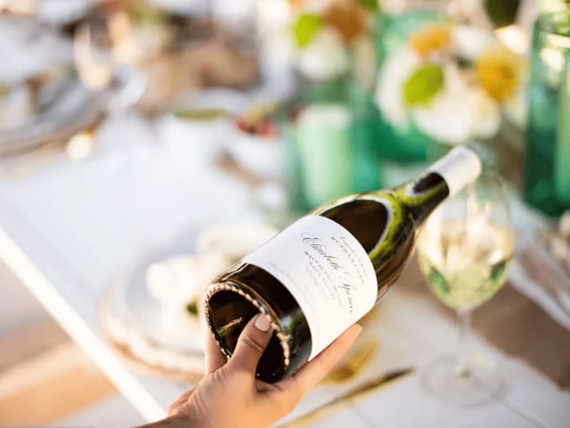 Hand holding wine bottle over elegant table setting