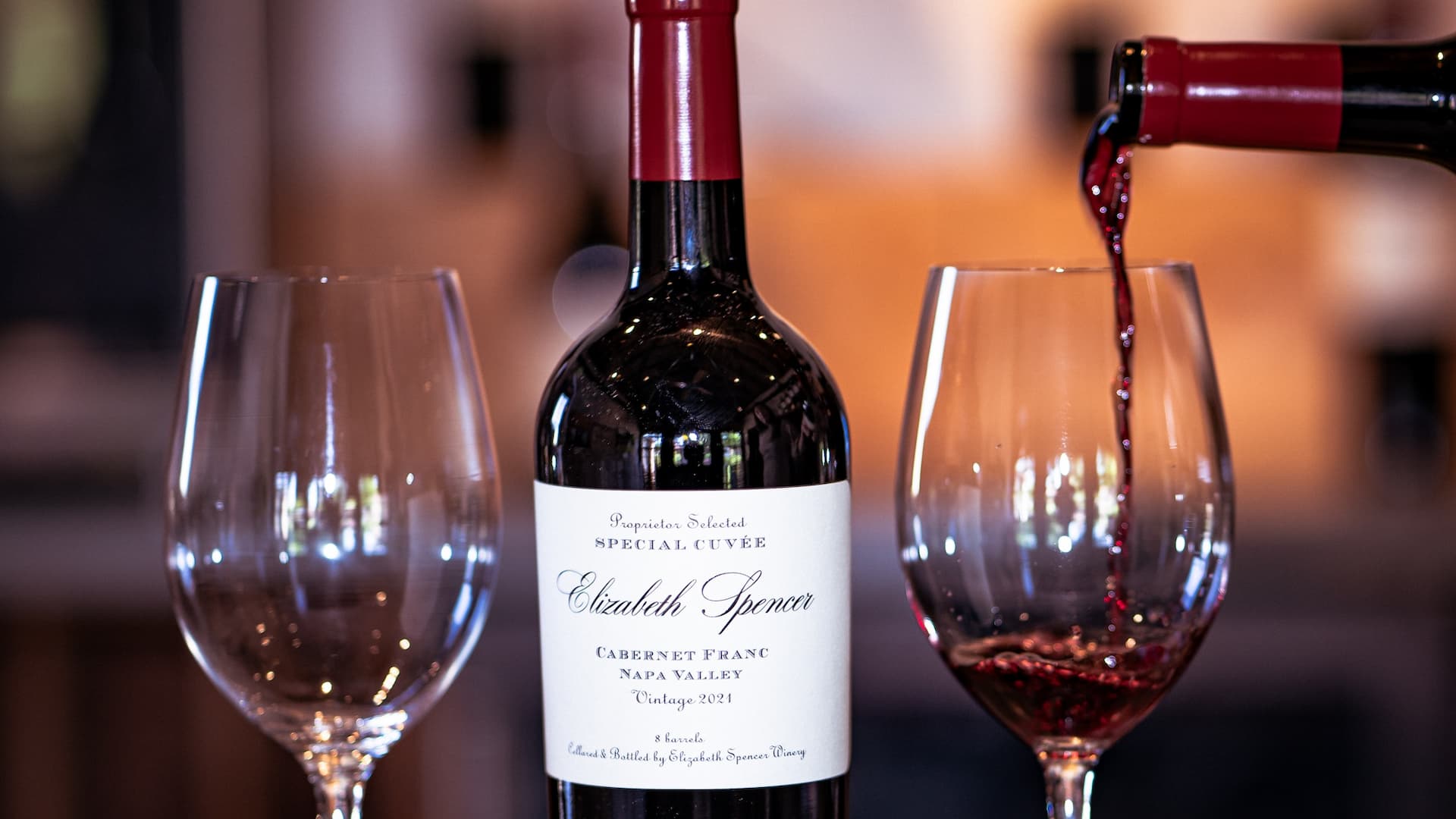 Pouring red wine next to bottle and glass.