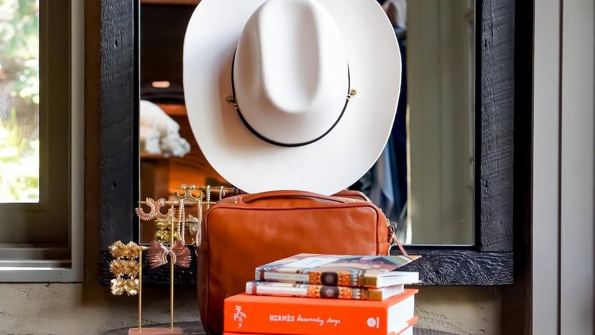 White hat on brown bag with books and jewelry.