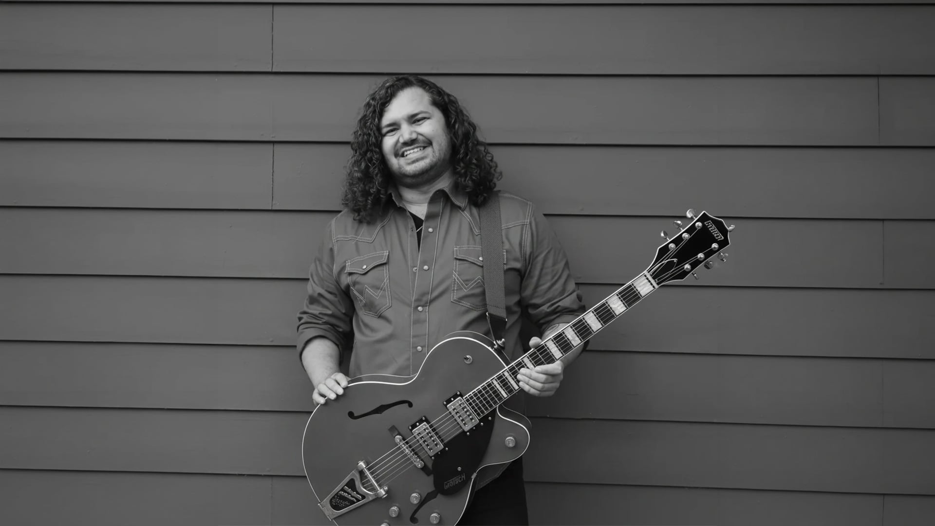 Smiling guitarist holding a hollow-body electric guitar