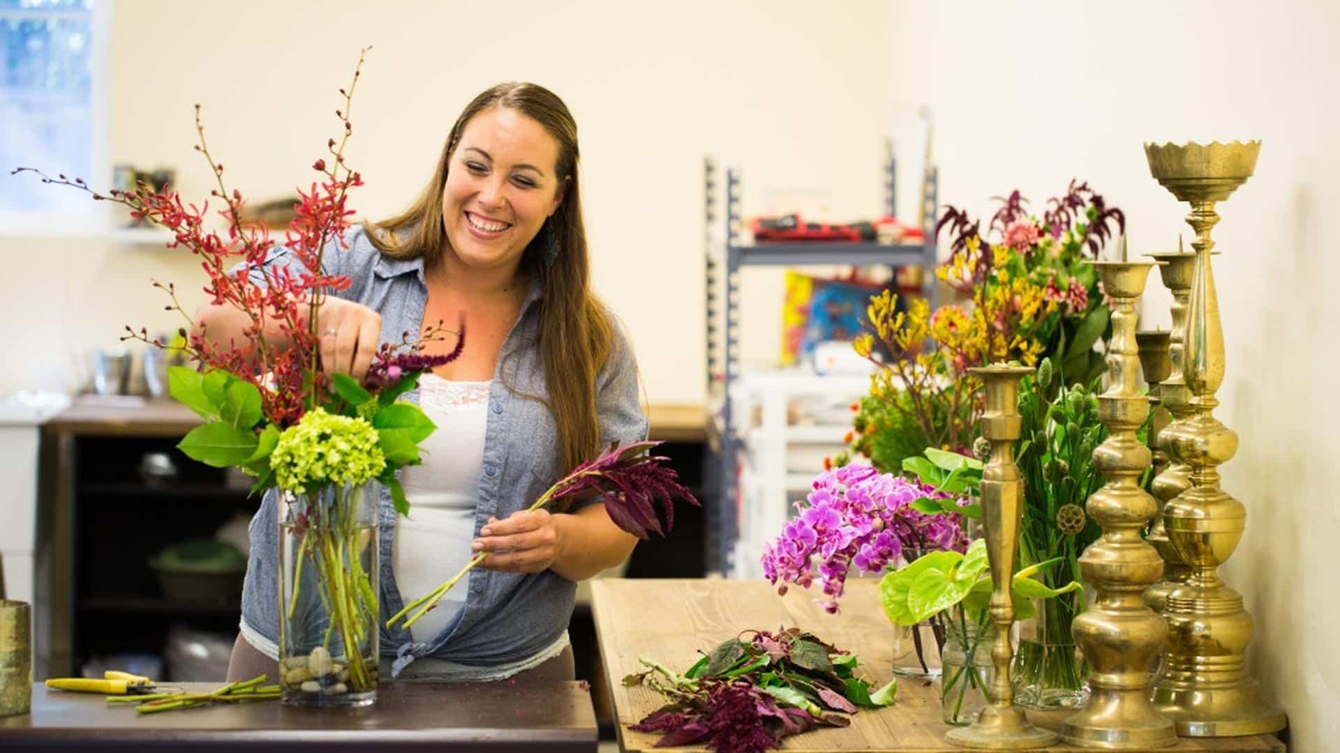 Woman creating a floral arrangement in workshop.