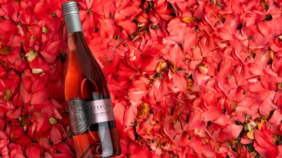 Bottle of rosé wine on pink petals.