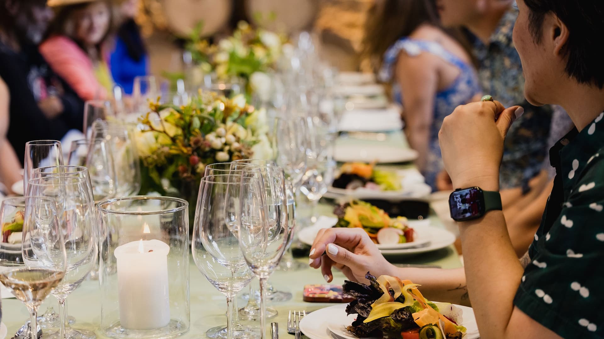 Group dining with salads and wine glasses.